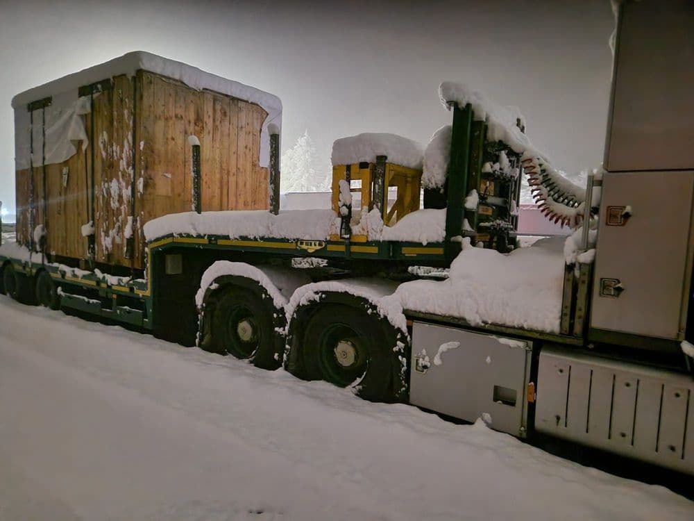 Semi-low-loader carrying a pressure vessel under a thick layer of snow on the way to Italy