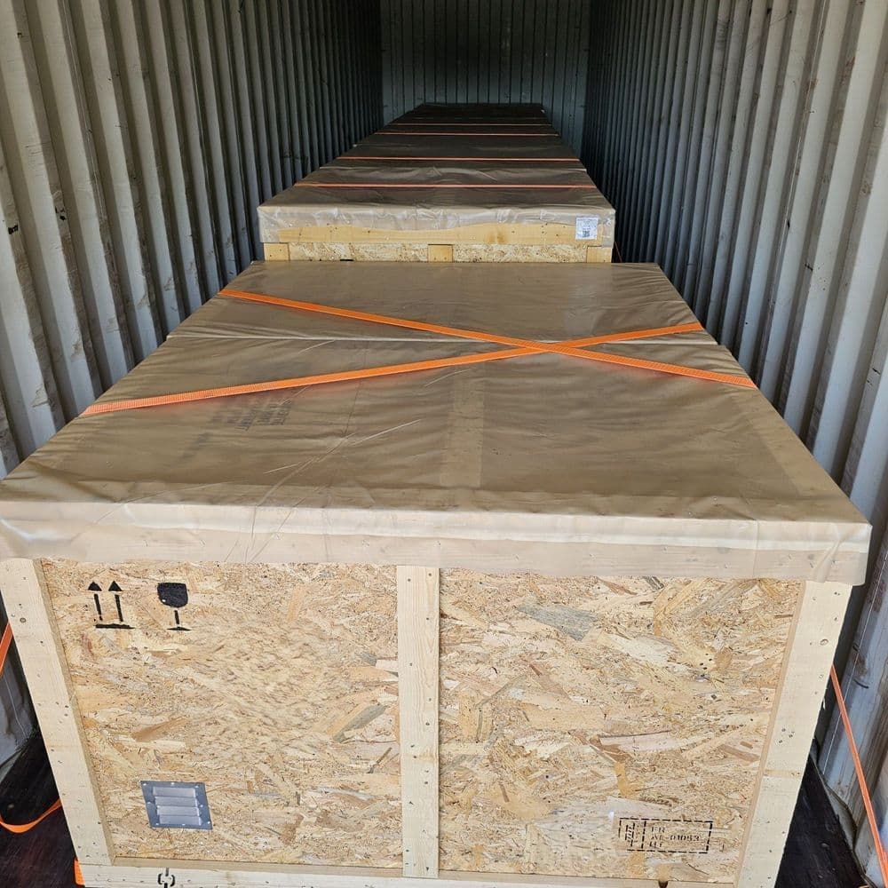 Conteneur maritime chargé de caisses en bois arrimées, prêt pour le transport maritime.